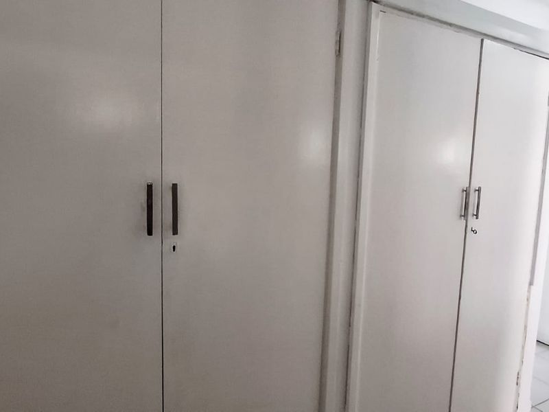 A functional hallway featuring built-in storage cupboards and tiled flooring, providing clean and practical circulation space within the property.