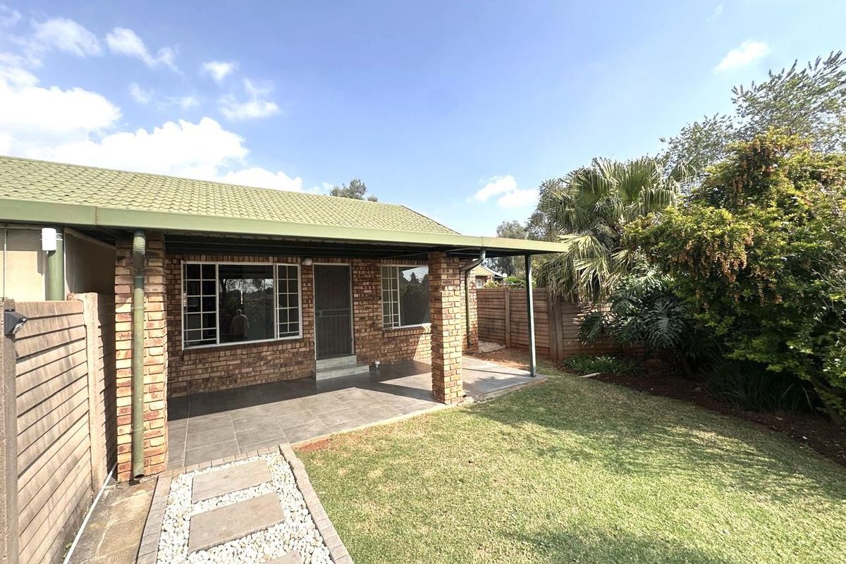 A well-maintained rear exterior featuring a covered tiled patio, brick facade, and a neat garden with a paved walkway.