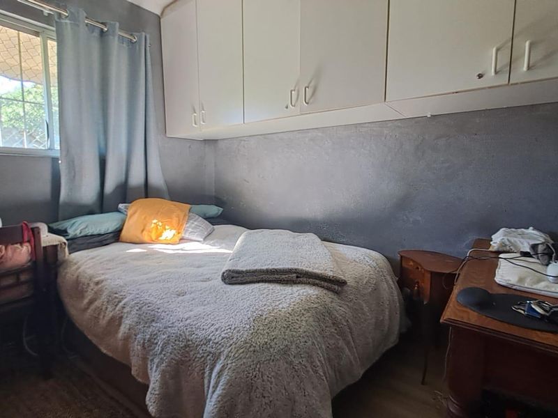A bedroom featuring built-in overhead storage cabinetry and a window fitted with security bars.