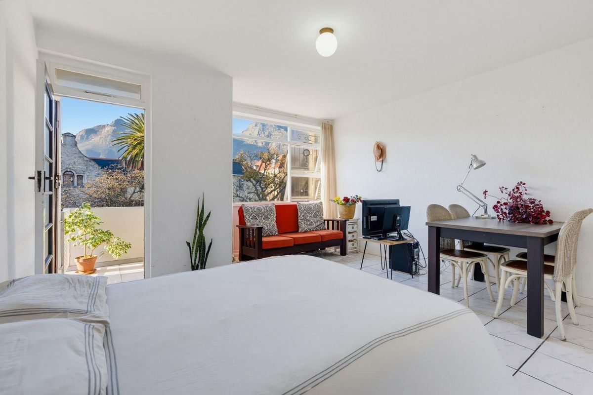 A bright bedroom featuring tiled flooring, a large window with mountain views, and direct access to a private balcony.