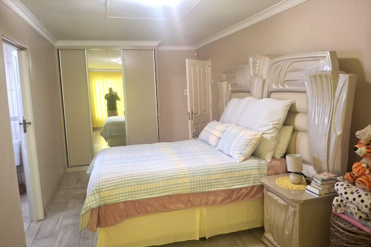 A bedroom featuring built-in cupboards with mirrored doors, ceiling cornice detailing, and tiled flooring.