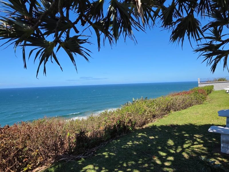 A scenic coastal view overlooking the ocean from a well-maintained garden area with established landscaping.