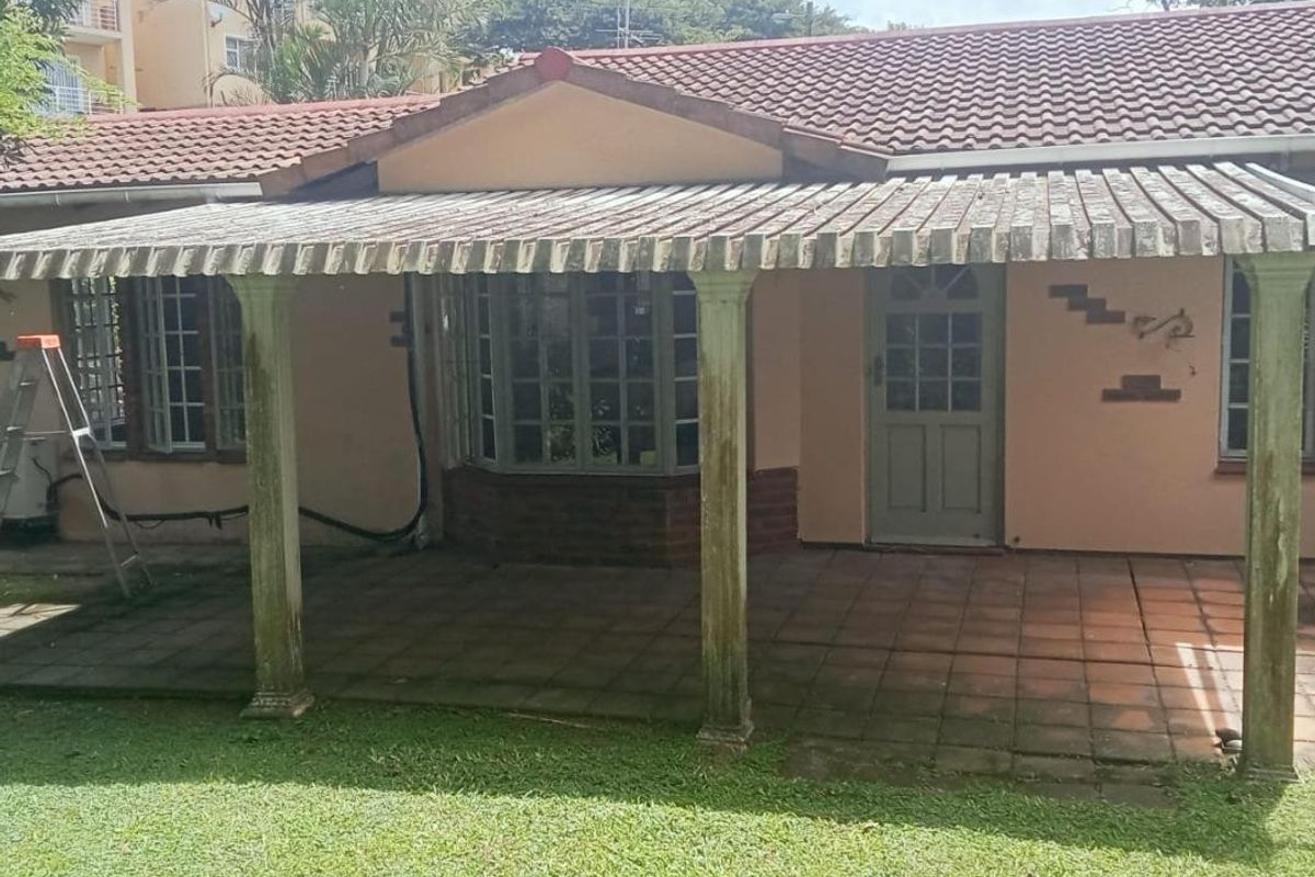 Rear exterior view of the townhouse featuring a covered patio area with a wooden pergola, terracotta roof tiles, and a bay window.