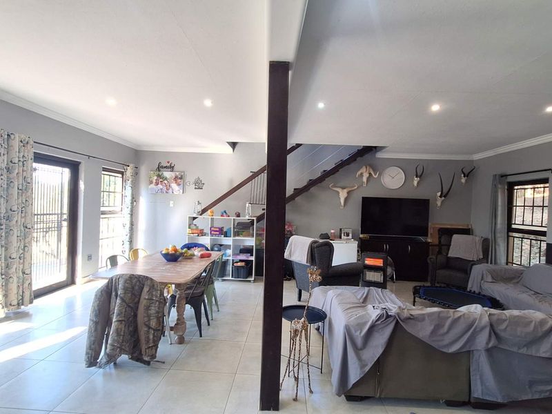 Spacious open-plan living and dining area featuring tiled flooring, recessed lighting, and a staircase, with direct access to the outdoor area via sliding doors.