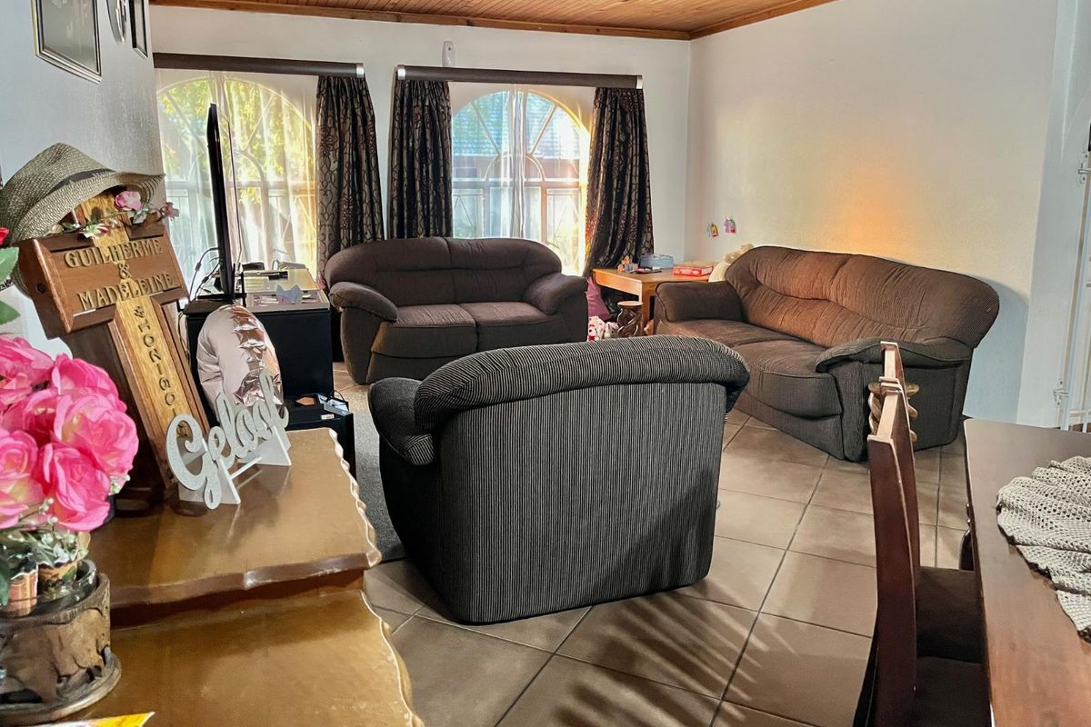 A living room featuring tiled flooring and a timber-clad ceiling, with large arched windows providing natural light.