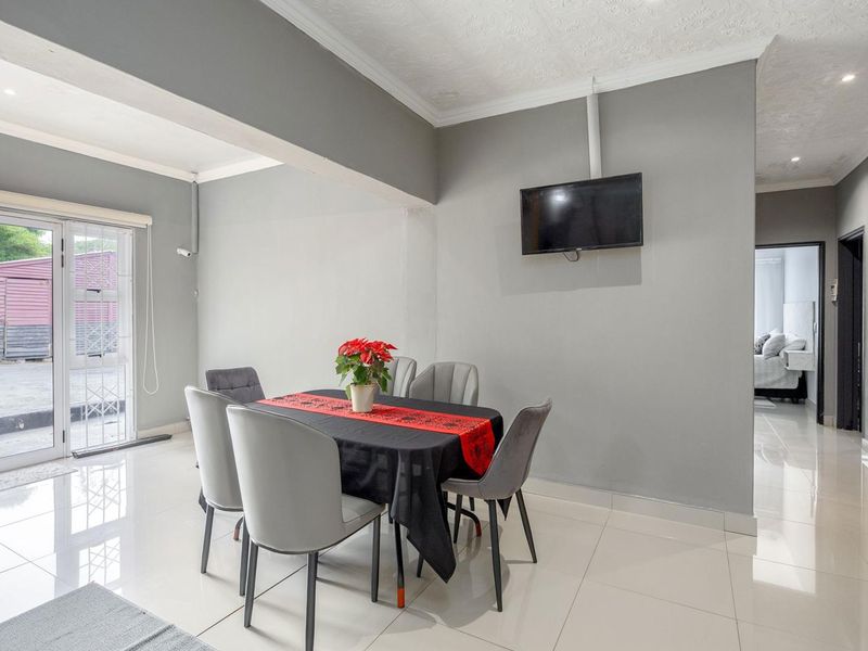 A bright dining area featuring polished tiled flooring, coved ceilings, and a sliding glass door providing access to the exterior.