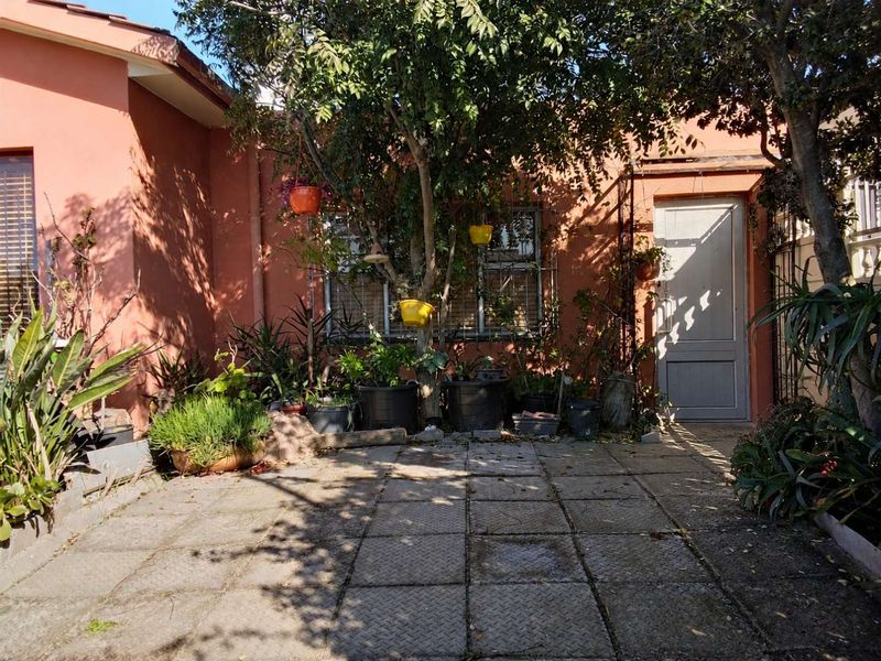A rear courtyard area featuring paved flooring, an exterior door, and security bars on the window, providing a private outdoor space.