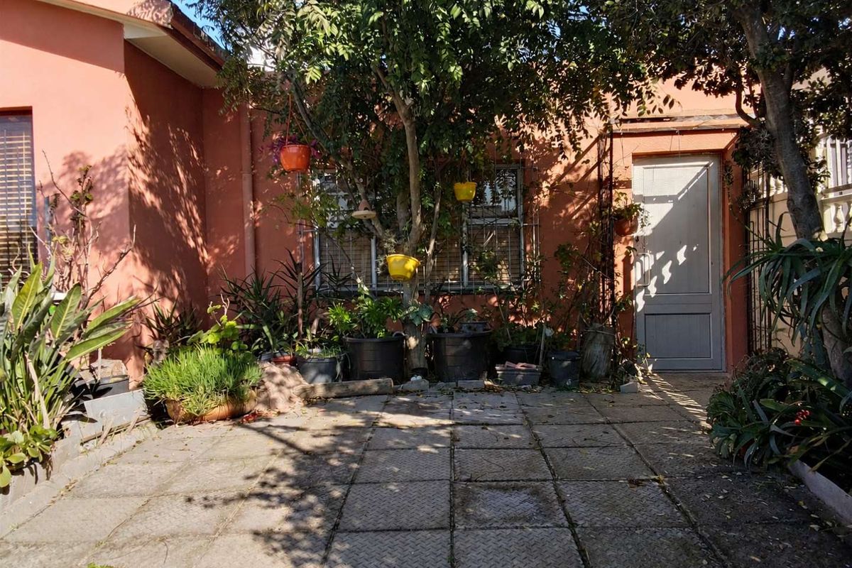 A rear courtyard area featuring paved flooring, an exterior door, and security bars on the window, providing a private outdoor space.