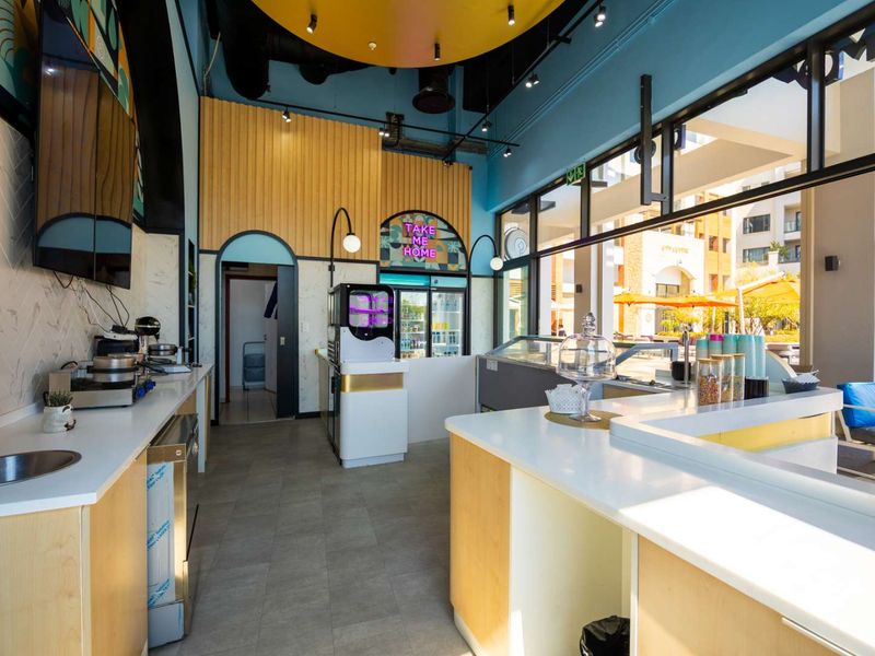 Modern commercial kitchen and service area featuring a clean service counter, tiled floors, and large glass windows overlooking the outdoor area.
