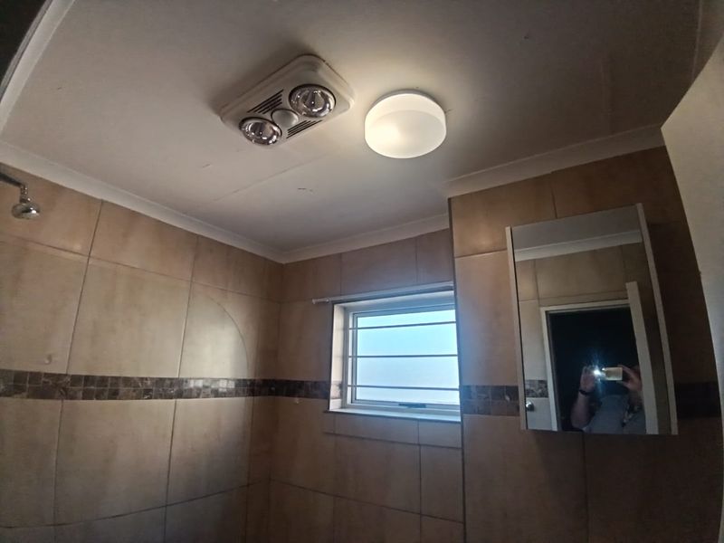 A functional bathroom featuring tiled walls, a heat lamp with extractor fan, and a mirrored medicine cabinet.