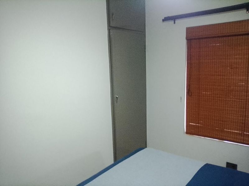 A bedroom featuring a built-in cupboard and a window with a fitted blind.