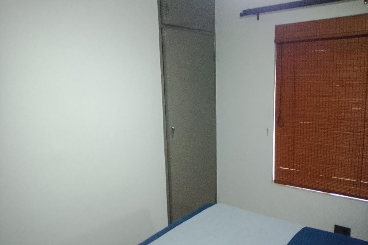 A bedroom featuring a built-in cupboard and a window with a fitted blind.