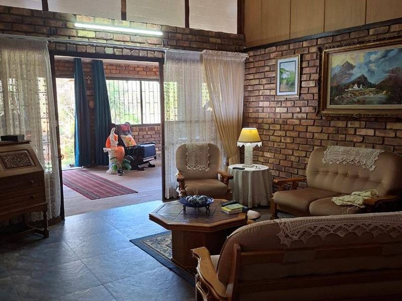 Spacious living room featuring exposed brick walls, vaulted ceilings, and large clerestory windows, providing access to an adjoining patio area.