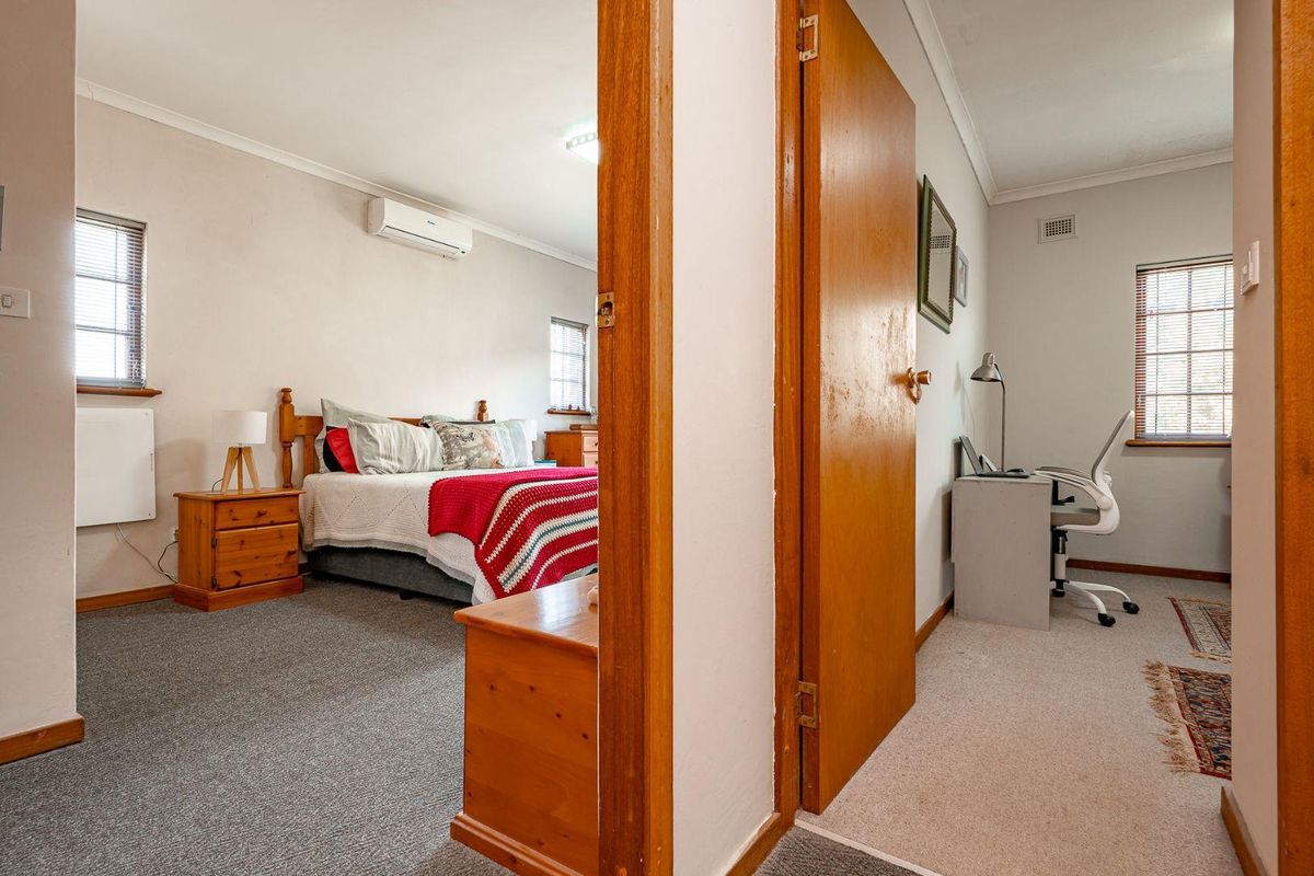A view from a hallway into a bedroom featuring carpeted flooring, a split-system air conditioner, and timber door frames.