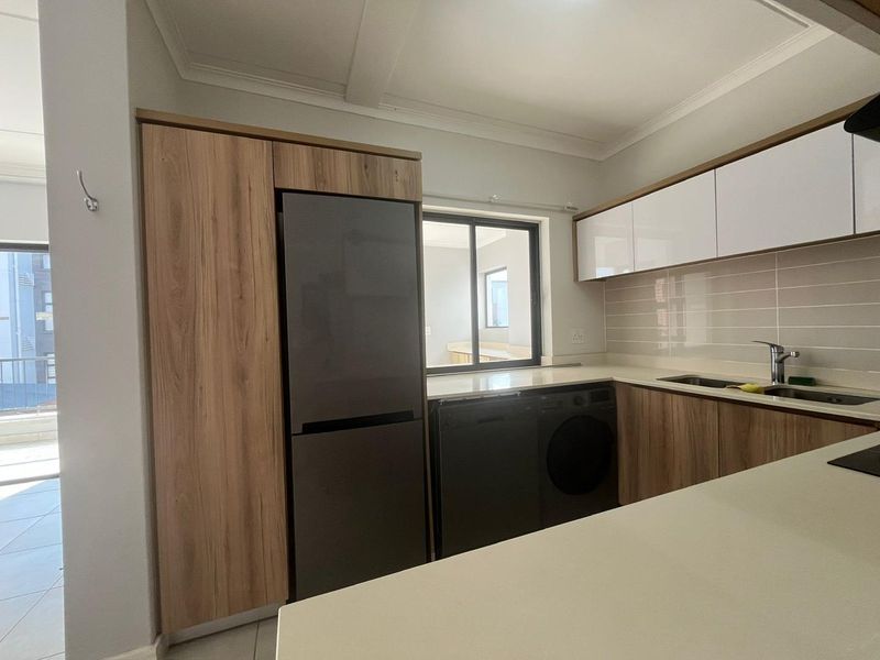 Modern kitchen featuring wood-grain and white cabinetry, stone countertops, tiled backsplash, and integrated appliance spaces, offering a clean and functional cooking area.
