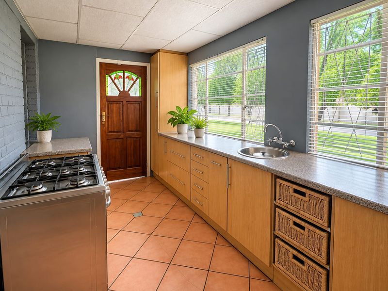 Functional kitchen featuring light wood cabinetry, granite-look countertops, gas stove, and tiled flooring with direct access to the exterior.