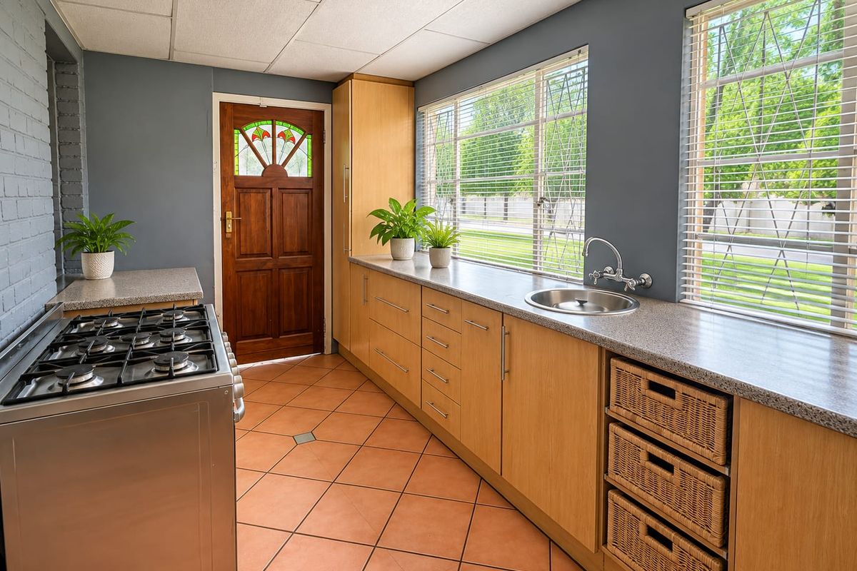 Functional kitchen featuring light wood cabinetry, granite-look countertops, gas stove, and tiled flooring with direct access to the exterior.