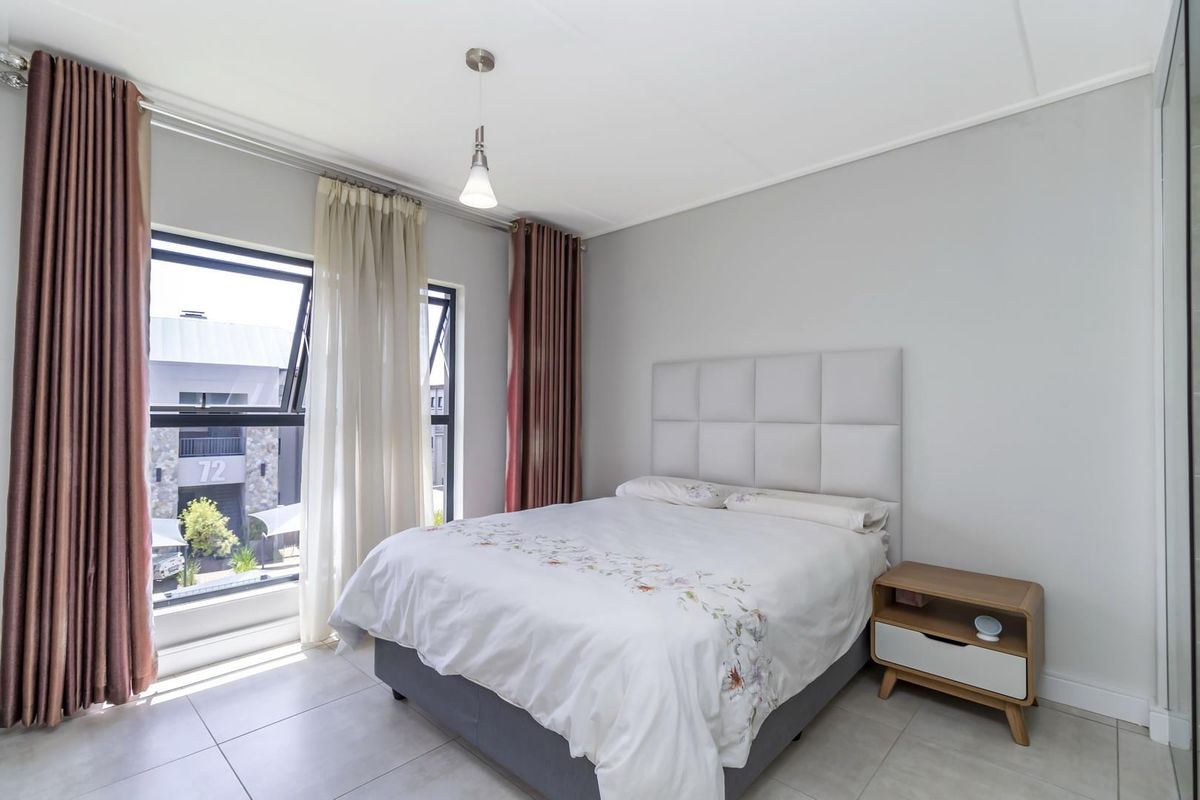 A bright and modern bedroom featuring tiled flooring, large windows with curtain tracks, and a neutral color palette.