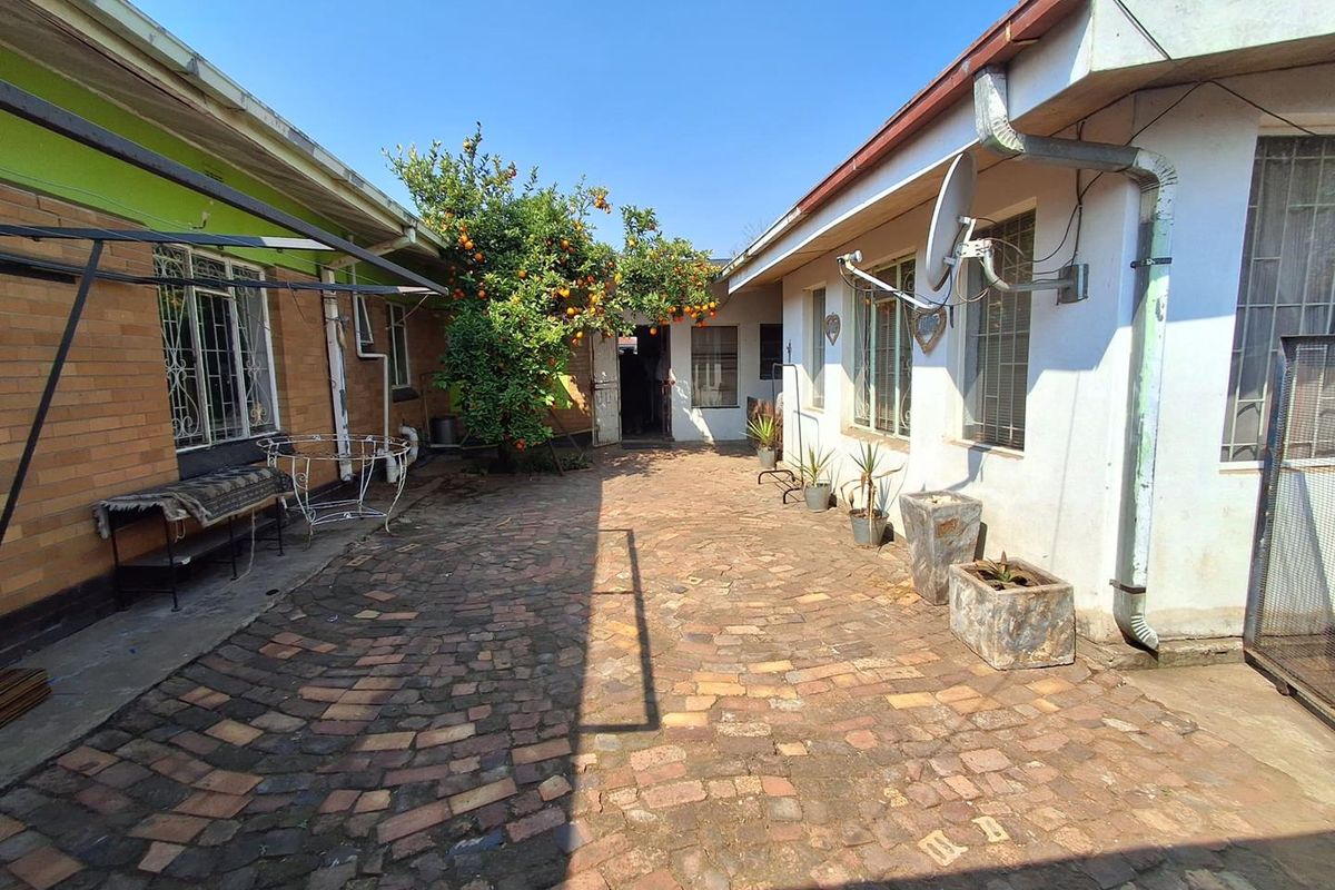 A rear courtyard area featuring brick paving, established citrus tree, and access to the main dwelling structure.