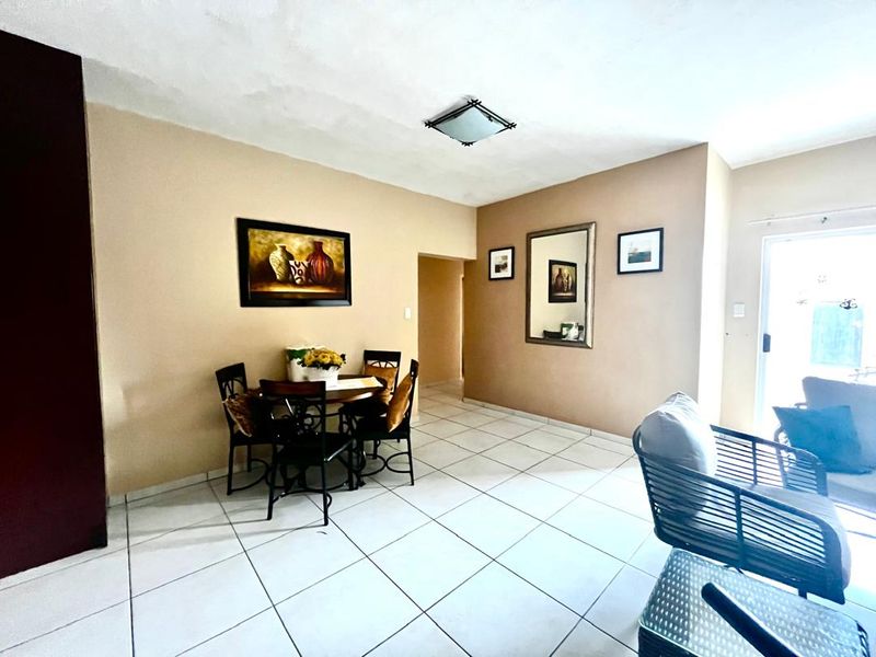 Open plan living and dining area featuring neutral wall tones and tiled flooring throughout.