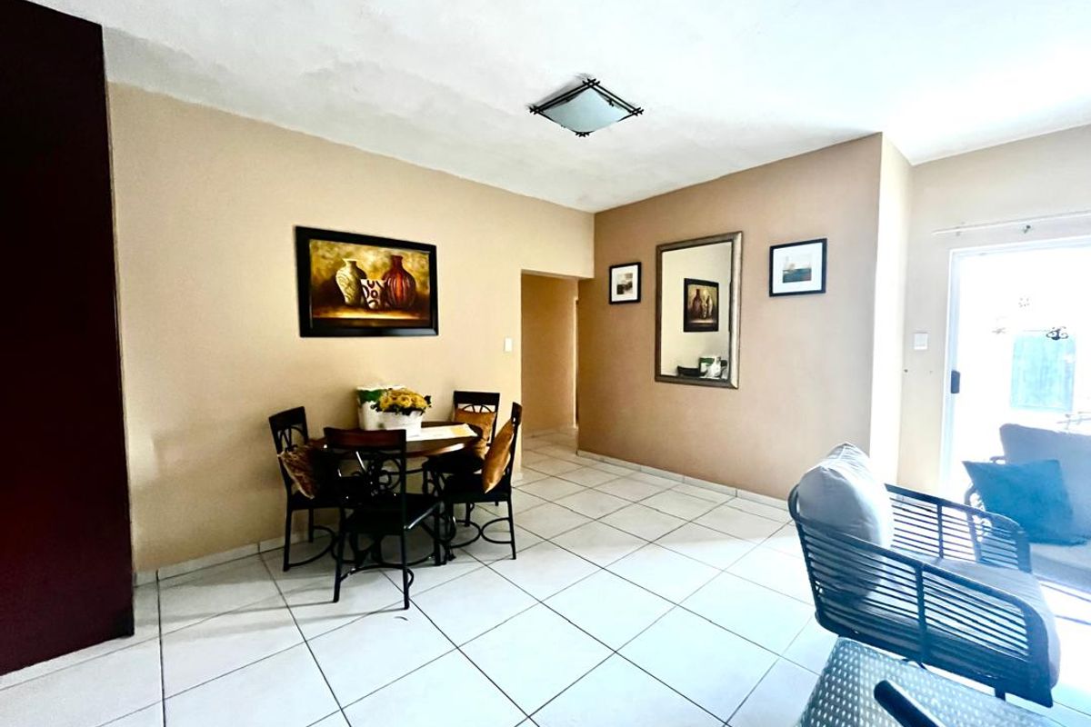 Open plan living and dining area featuring neutral wall tones and tiled flooring throughout.