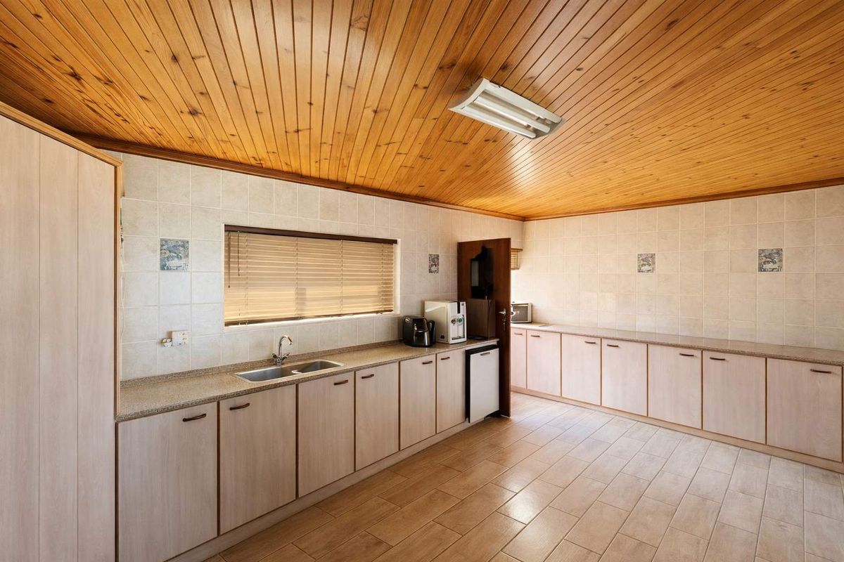Spacious kitchen featuring extensive laminate cabinetry, double bowl sink, tiled splashback, and a distinctive timber tongue and groove ceiling.