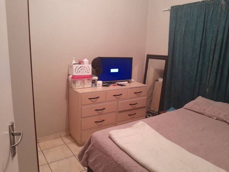 A standard bedroom featuring tiled flooring and a built-in cupboard, providing functional storage space.