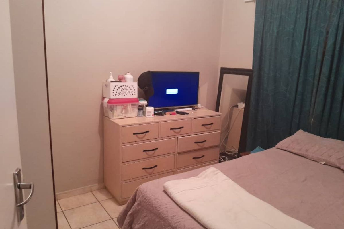 A standard bedroom featuring tiled flooring and a built-in cupboard, providing functional storage space.