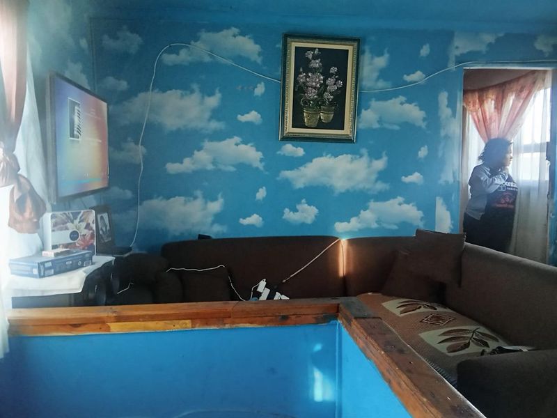 A living room area featuring cloud-patterned wallpaper and timber trim, requiring cosmetic updates to improve the overall aesthetic and finish.