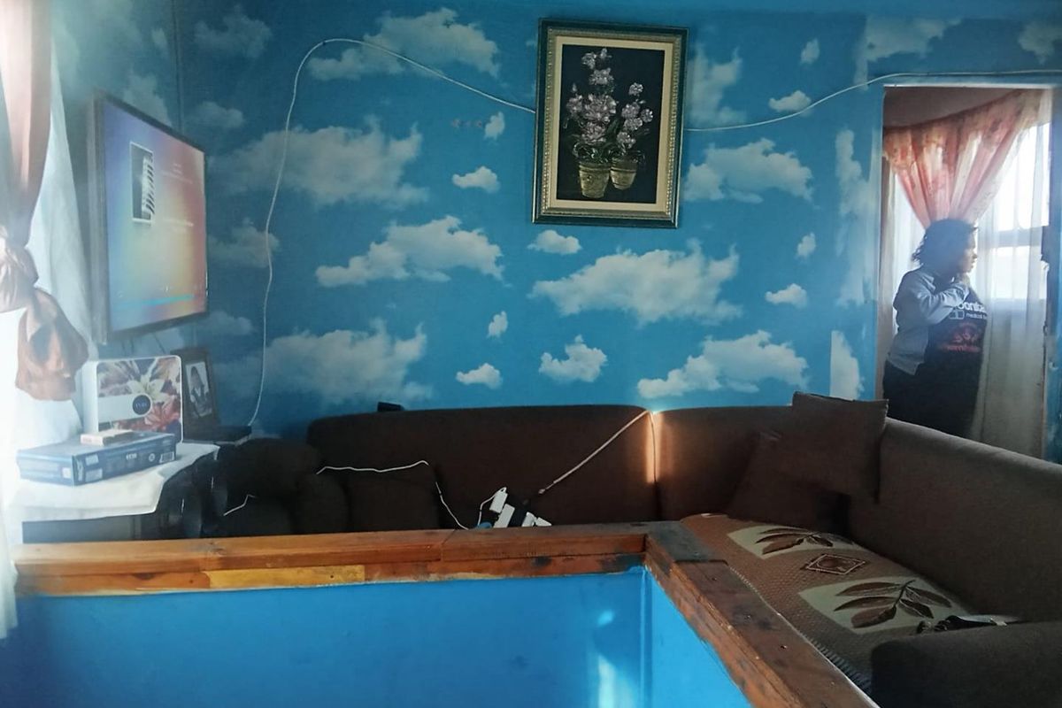 A living room area featuring cloud-patterned wallpaper and timber trim, requiring cosmetic updates to improve the overall aesthetic and finish.