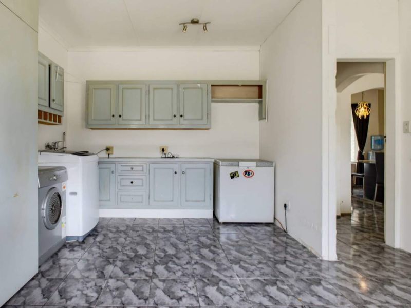 A functional laundry room featuring tiled flooring and built-in cabinetry with space for laundry appliances.