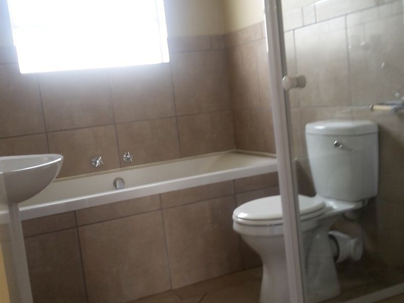 A functional bathroom featuring a built-in bathtub, pedestal basin, toilet, and a separate shower enclosure with tiled finishes throughout.