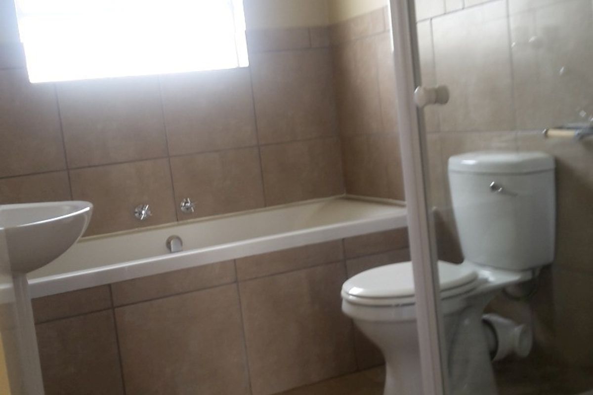 A functional bathroom featuring a built-in bathtub, pedestal basin, toilet, and a separate shower enclosure with tiled finishes throughout.