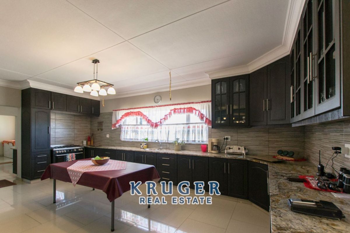 Spacious kitchen featuring dark cabinetry, granite countertops, tiled backsplash, and a built-in stove, offering ample storage and workspace.