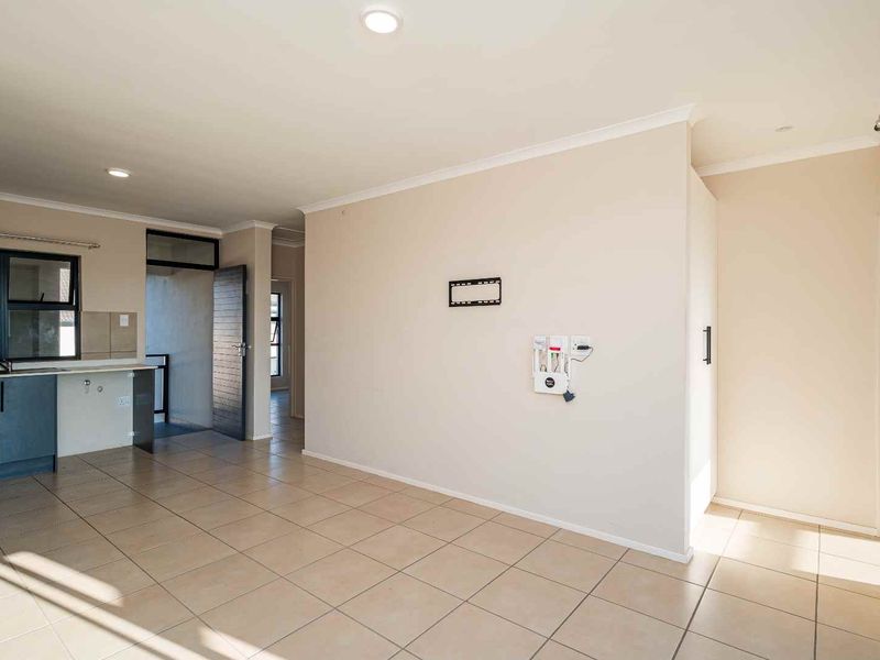 Spacious open-plan living area featuring neutral tiled flooring, recessed lighting, and an integrated kitchen space with modern cabinetry.