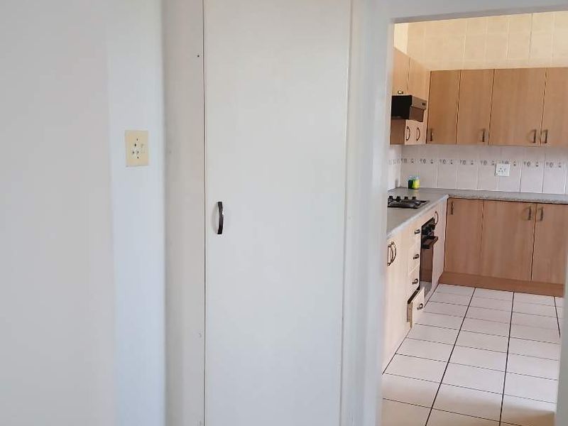 A functional kitchen featuring built-in cabinetry, a gas hob, and an oven, adjacent to a room with timber flooring.