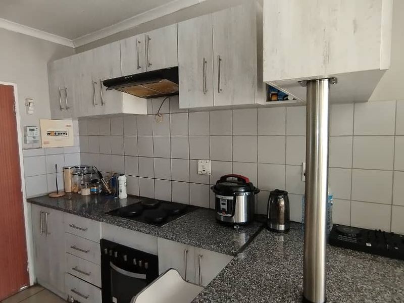 A functional kitchen featuring granite countertops, built-in oven, electric hob, extractor fan, and ample cabinetry with a breakfast bar.