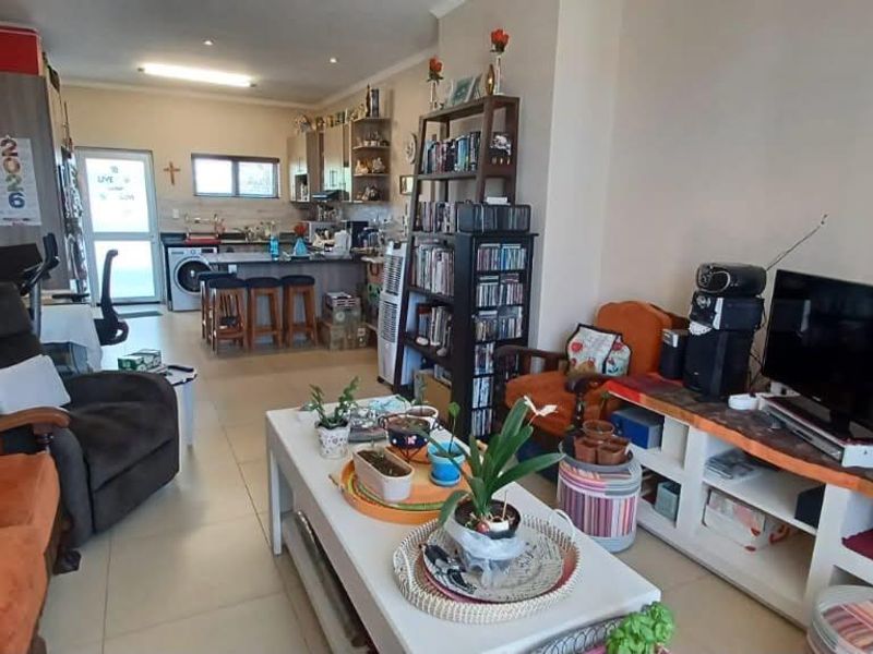 Open-plan living area featuring tiled floors and a combined kitchen space with a breakfast island and integrated laundry area.