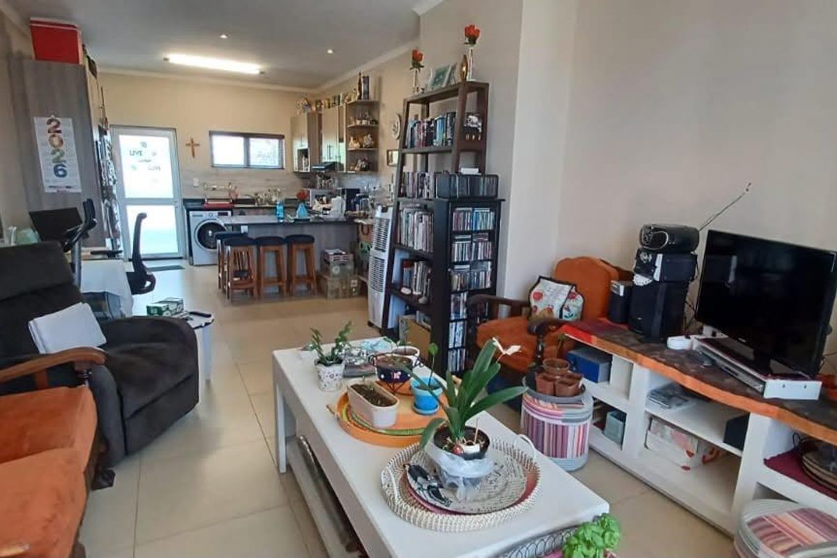 Open-plan living area featuring tiled floors and a combined kitchen space with a breakfast island and integrated laundry area.