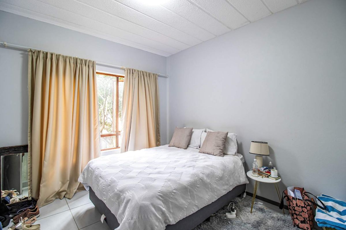 A bedroom featuring tiled flooring, a window with curtain tracks, and a textured ceiling finish.