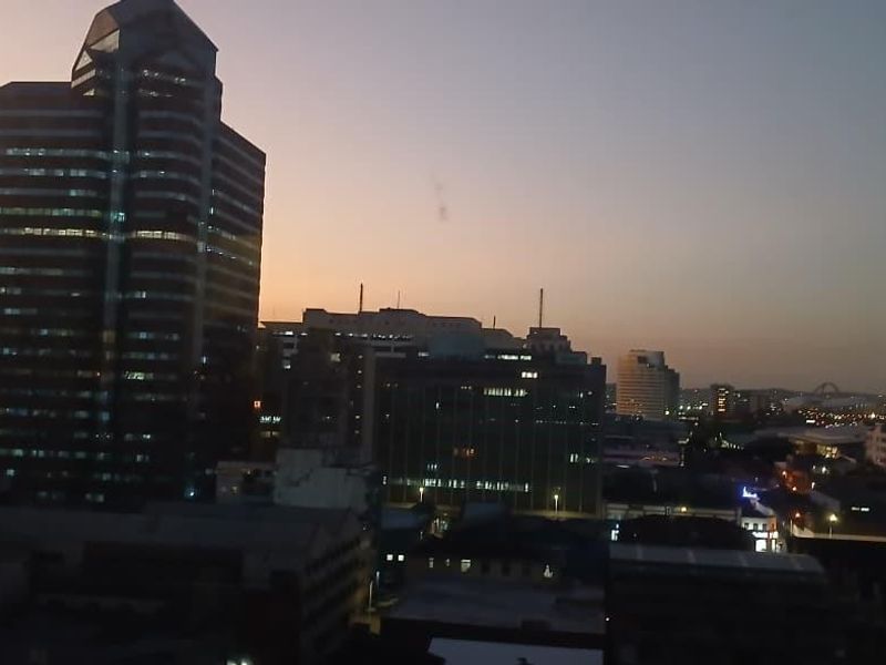 An elevated city skyline view at dusk, showcasing surrounding urban architecture and high-rise buildings.