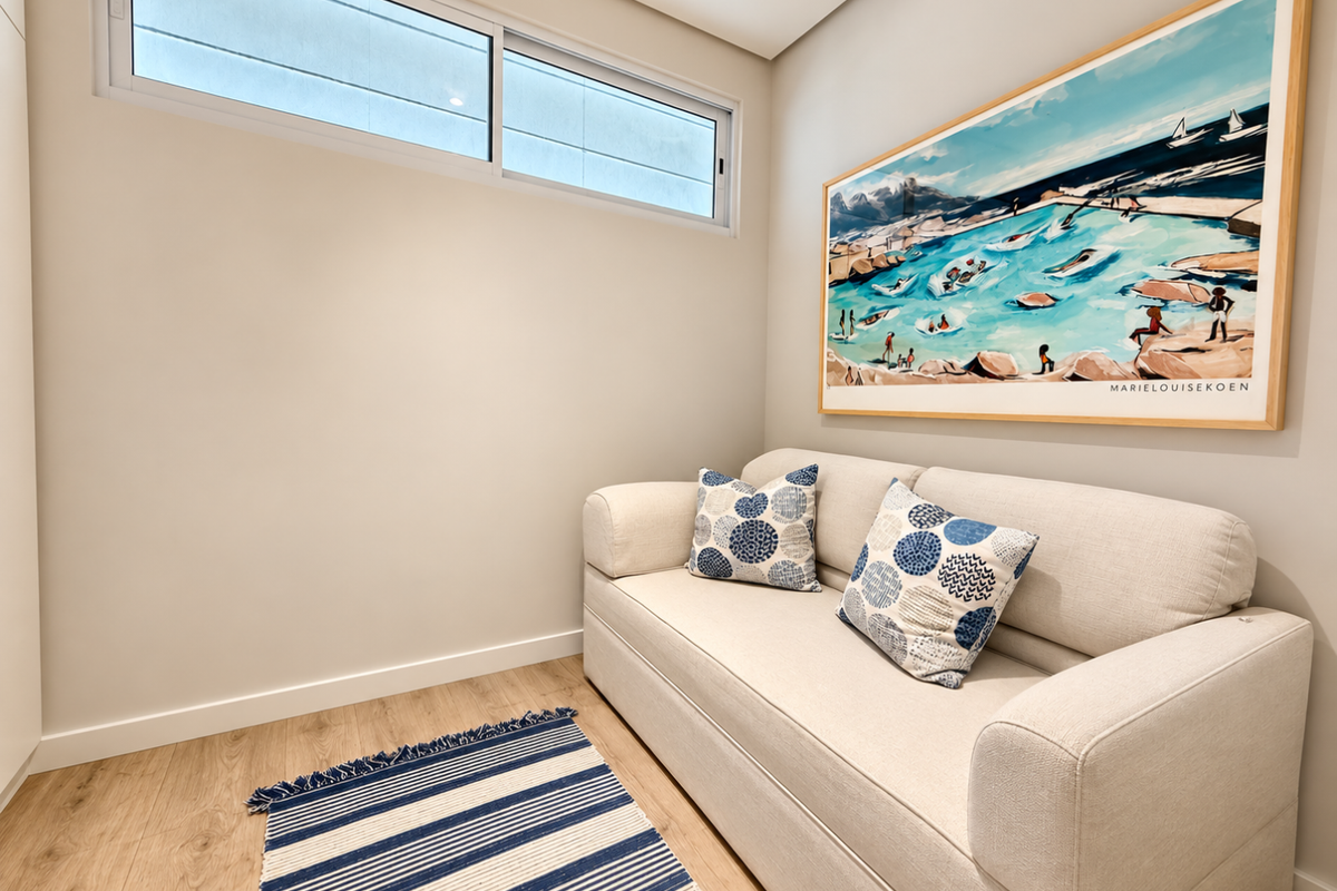 A bright and modern living space featuring light laminate flooring, neutral walls, and a high-set horizontal window providing natural light.