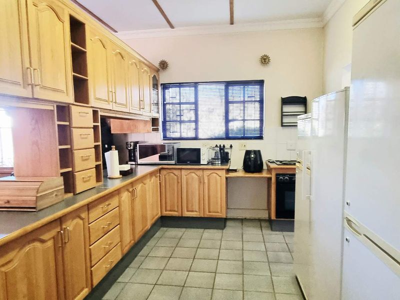 A functional kitchen featuring extensive wooden cabinetry, tiled flooring, and a built-in oven, offering a traditional layout with ample storage space.