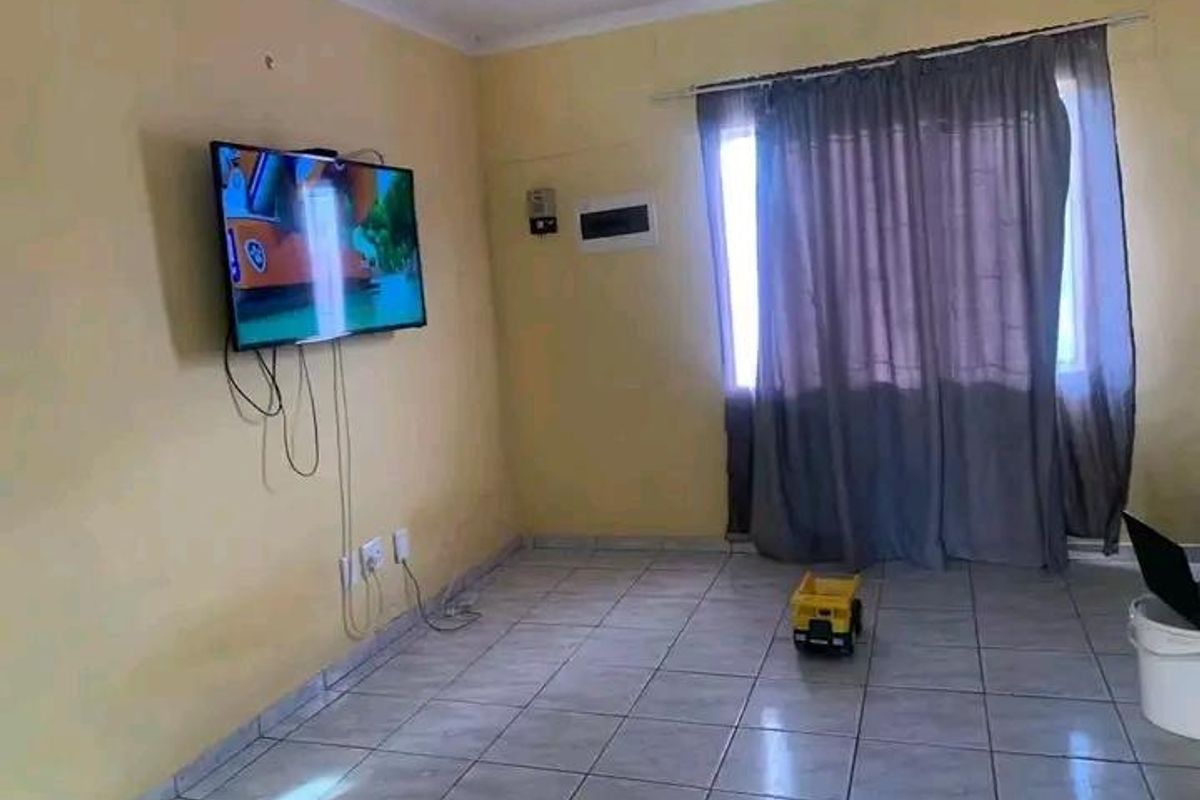 A simple living room area featuring tiled flooring and wall-mounted electrical points, offering a blank canvas for potential interior updates.