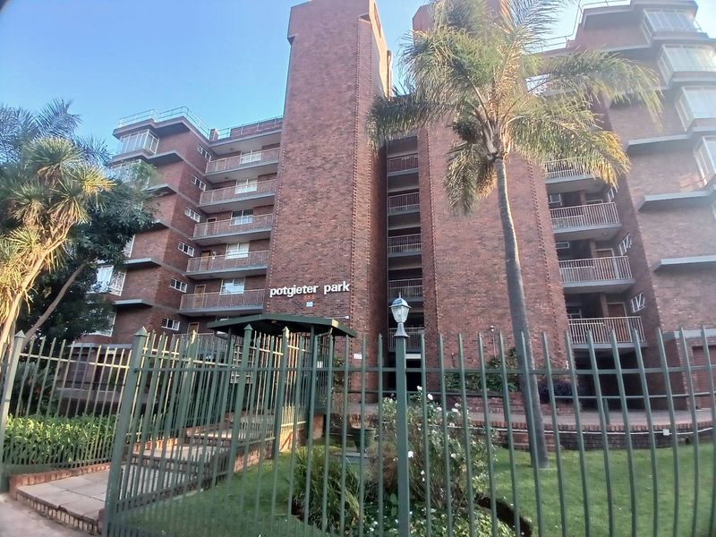 Front elevation of Potgieter Park apartment complex featuring a multi-story brick facade with private balconies and secure perimeter fencing.