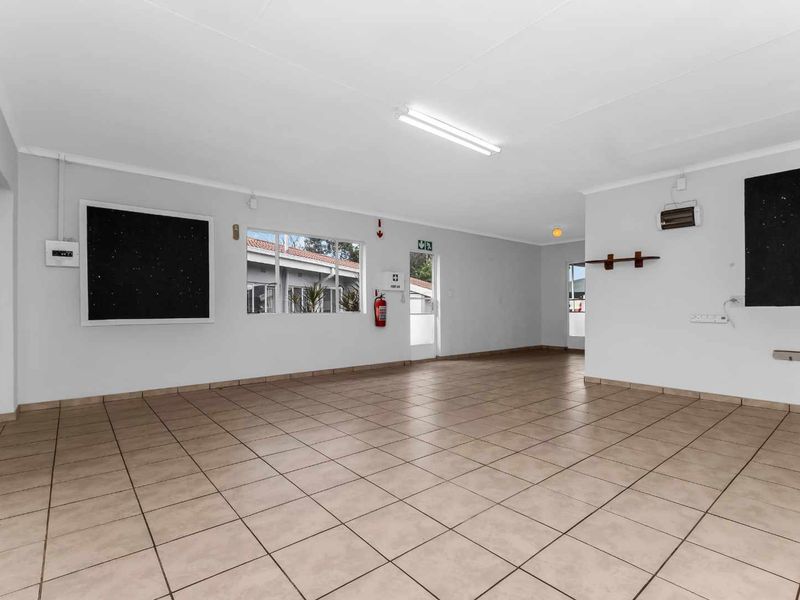 A spacious, open-plan interior area featuring neutral tiled flooring, ample natural light, and functional utility fixtures, suitable for various commercial or residential uses.