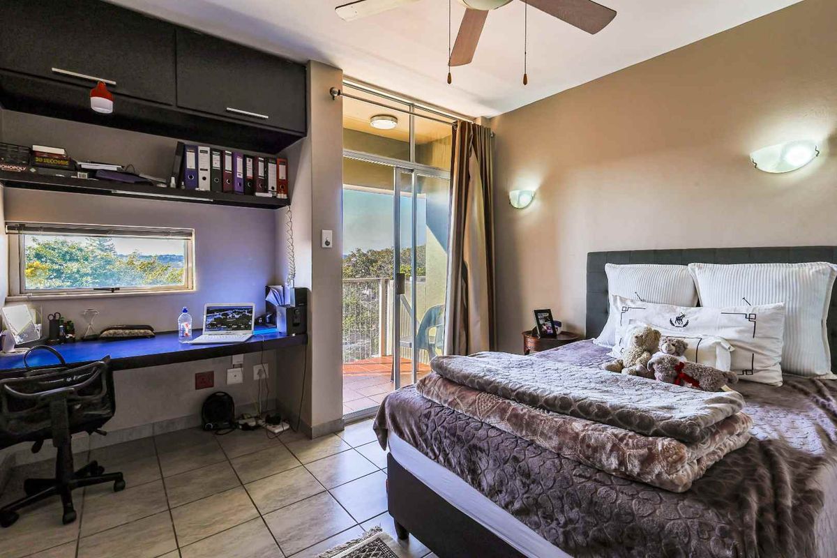 Bedroom featuring a built-in desk with overhead cabinetry, tiled flooring, ceiling fan, and sliding glass door access to a private balcony.