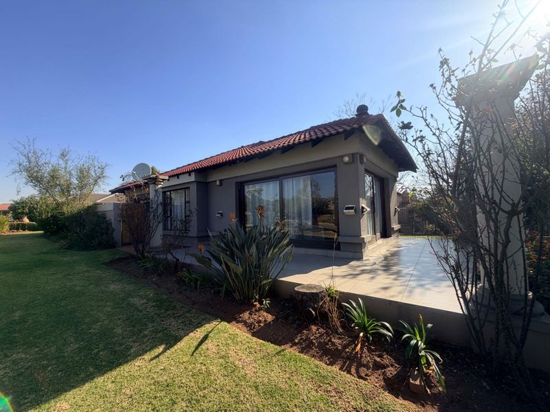 Rear view of the house featuring a tiled patio area, sliding glass doors, and a well-maintained garden setting.