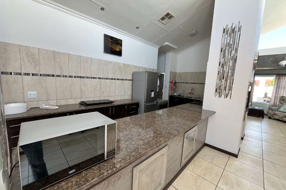 A functional kitchen featuring granite countertops, extensive built-in cabinetry, tiled backsplash, and a breakfast bar area, providing ample workspace and storage.