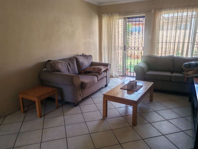 A living room featuring ceramic floor tiles and a sliding glass door with a security gate providing access to the exterior.